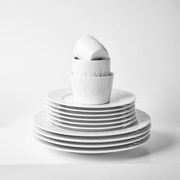 Stack of white porcelain plates and bowls with subtle Scandinavian design by Frederik Bagger