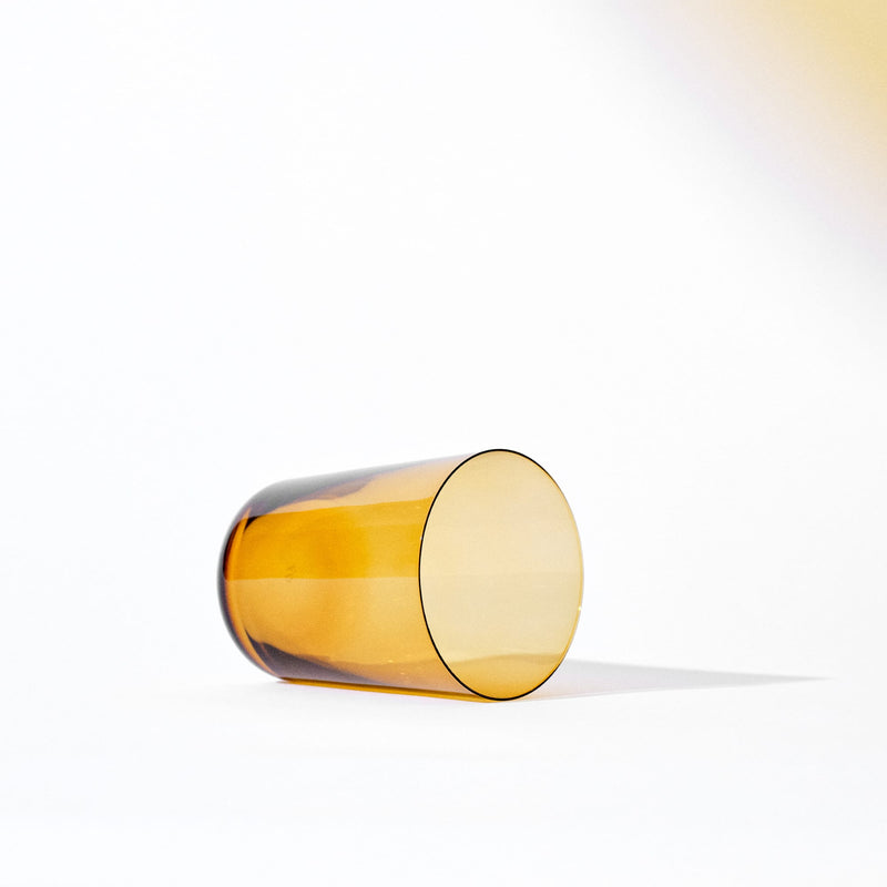 Amber-hued cylindrical water glass with Scandinavian minimal design, showcasing colored crystal and refined finish.