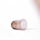 Minimalist Scandinavian clear brown glass tumbler laying on its side with soft shadow on white background