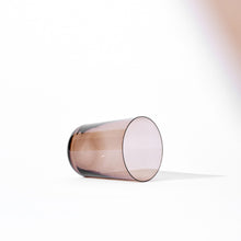 Minimalist Scandinavian clear brown glass tumbler laying on its side with soft shadow on white background